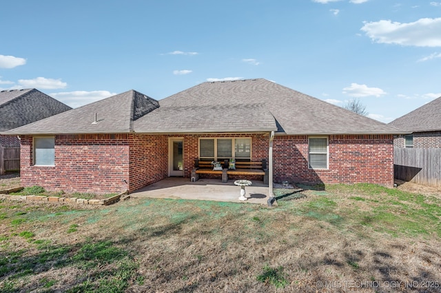 rear view of property with a patio area, brick siding, fence, and roof with shingles