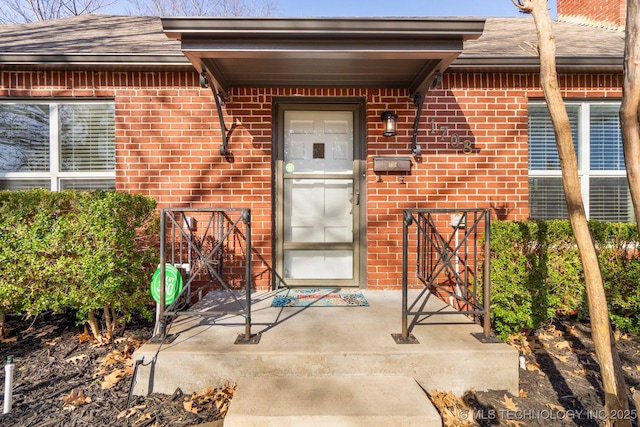 entrance to property with brick siding and roof with shingles