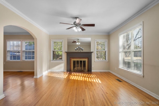 unfurnished living room featuring visible vents, light wood finished floors, a fireplace, ceiling fan, and crown molding