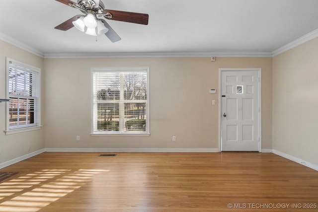 unfurnished room with crown molding, a healthy amount of sunlight, light wood-style floors, and visible vents