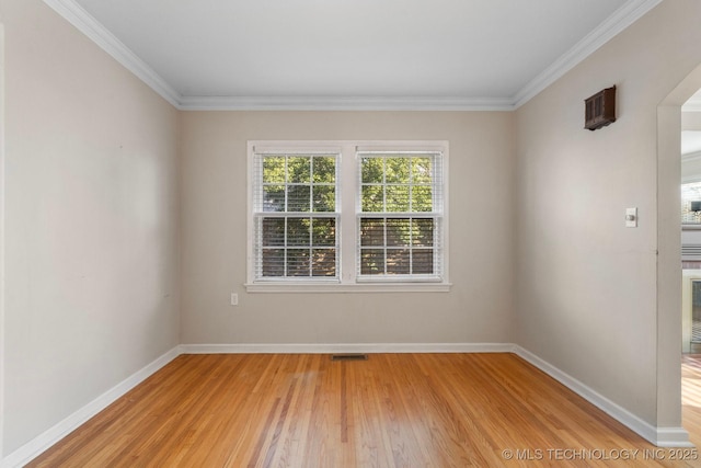 empty room with visible vents, light wood-style flooring, crown molding, and baseboards