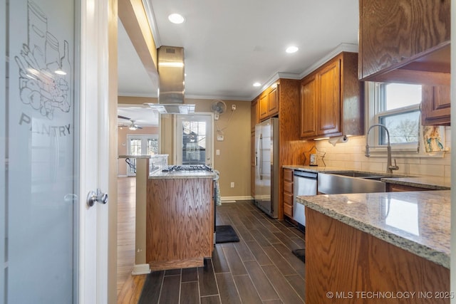 kitchen with brown cabinetry, wood tiled floor, a sink, decorative backsplash, and stainless steel appliances