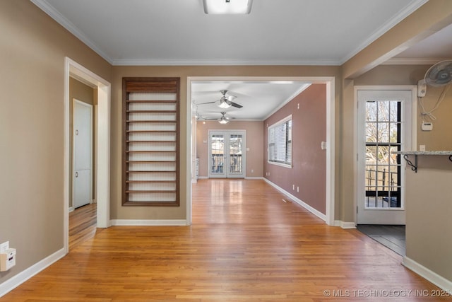 interior space with light wood finished floors, baseboards, ceiling fan, and ornamental molding