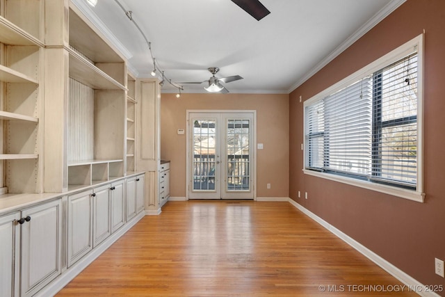 unfurnished dining area with ornamental molding, a ceiling fan, light wood-style floors, and baseboards