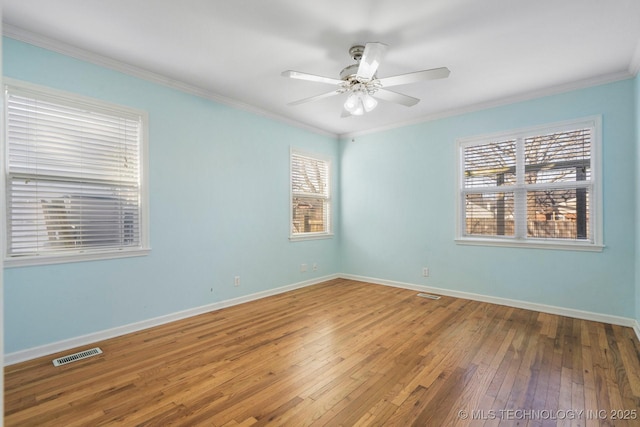 empty room with visible vents, crown molding, baseboards, a ceiling fan, and wood-type flooring