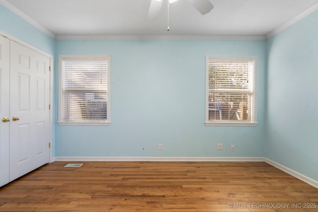 unfurnished bedroom featuring visible vents, baseboards, wood finished floors, and ornamental molding