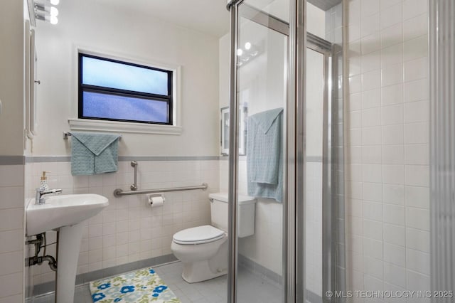 full bathroom featuring tile patterned flooring, a shower stall, wainscoting, tile walls, and toilet