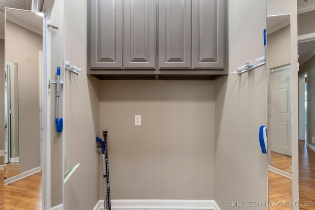 clothes washing area with light wood-type flooring, baseboards, and cabinet space