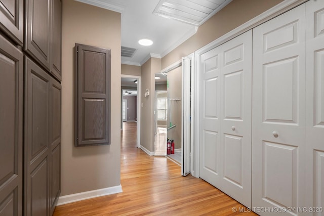 hallway featuring light wood finished floors, visible vents, crown molding, and baseboards