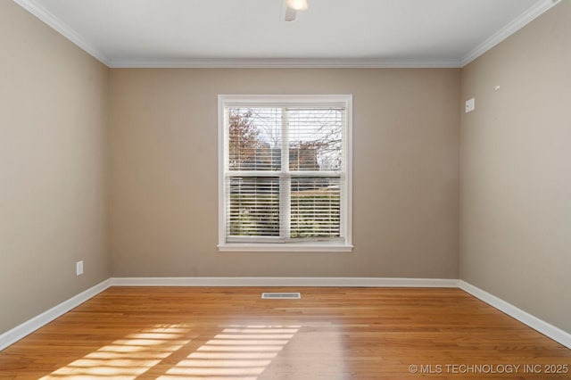 unfurnished room with visible vents, ornamental molding, baseboards, and wood finished floors