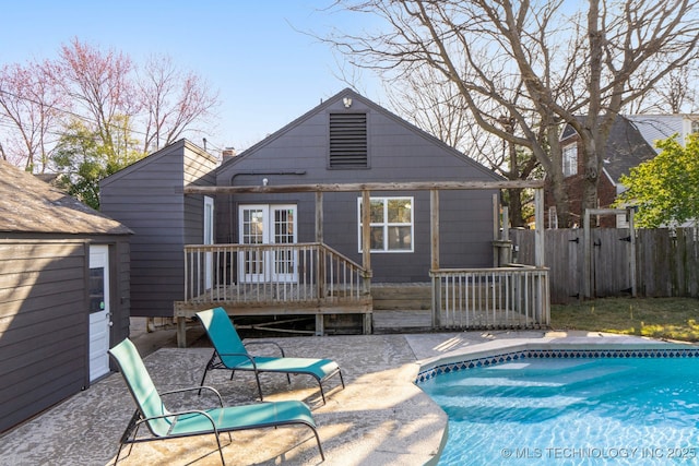 rear view of property featuring a patio, fence, a fenced in pool, and a wooden deck