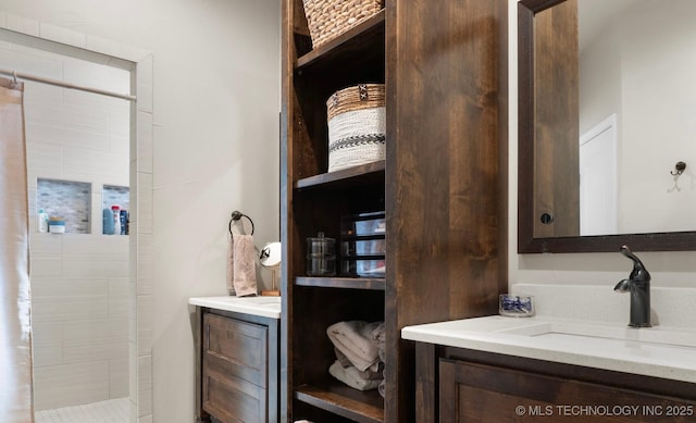 bathroom with a tile shower and vanity