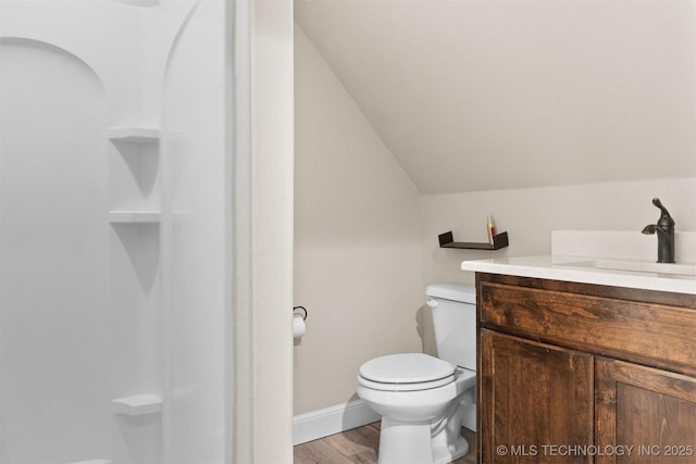 bathroom featuring toilet, vaulted ceiling, vanity, wood finished floors, and baseboards