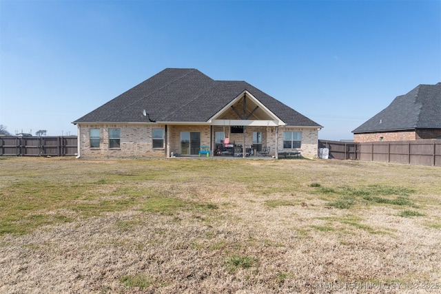 rear view of property with brick siding, a fenced backyard, a patio, and a yard