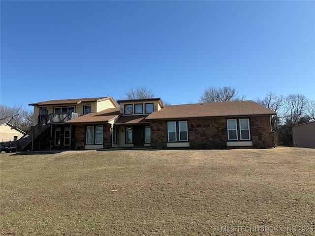 view of front of home with a front yard, stone siding, and stairway