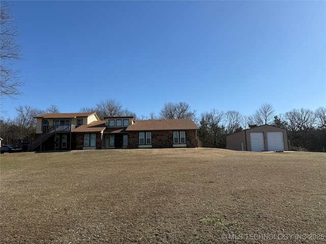 view of front of home featuring a garage, a front lawn, an outbuilding, and stairs