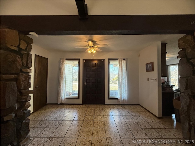 entryway featuring beamed ceiling, a ceiling fan, and baseboards