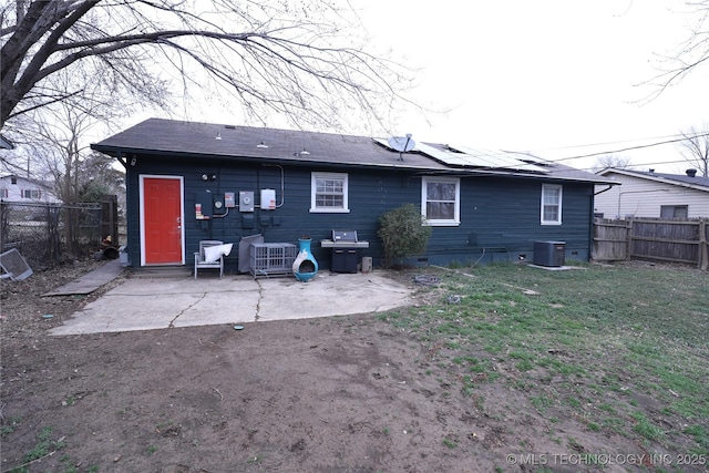 rear view of house with cooling unit, crawl space, a fenced backyard, and roof mounted solar panels