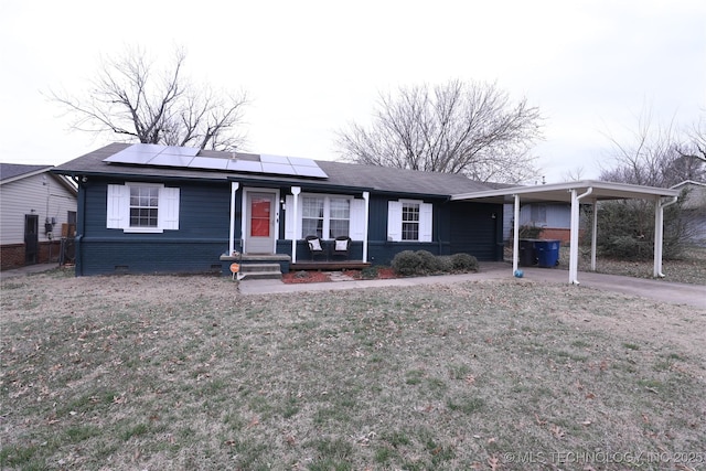 single story home featuring solar panels, concrete driveway, an attached carport, a front lawn, and brick siding