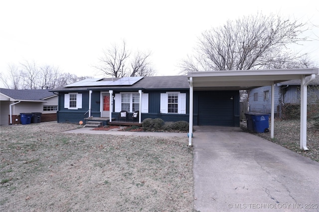 ranch-style house featuring roof with shingles, an attached carport, solar panels, and concrete driveway