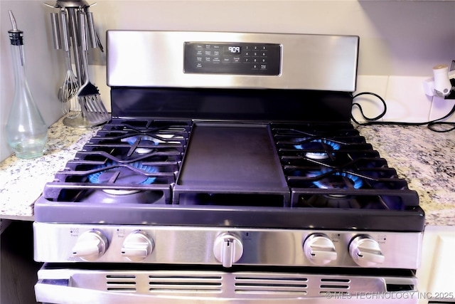 details featuring light stone counters and stainless steel range with gas cooktop