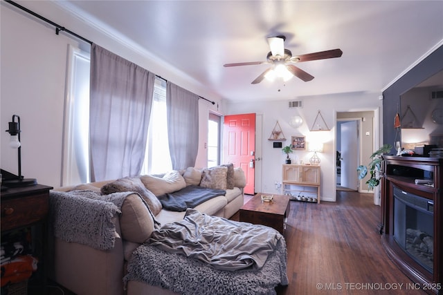 living room with dark wood-style floors, visible vents, and a ceiling fan