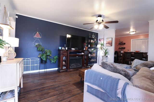 living room featuring ceiling fan, a fireplace, crown molding, and wood finished floors