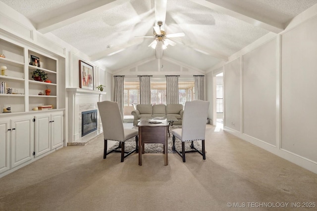 living area featuring vaulted ceiling with beams, a high end fireplace, a textured ceiling, and light colored carpet