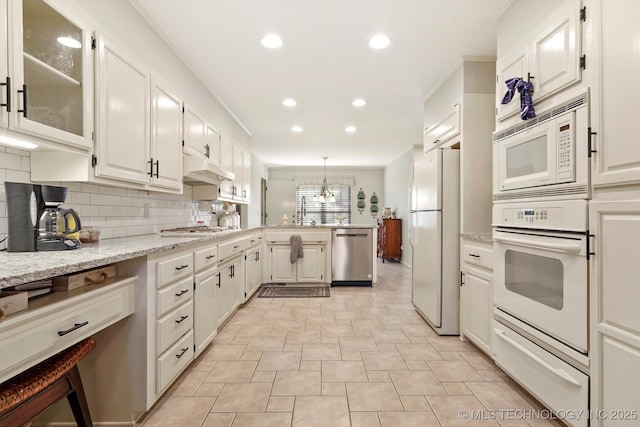 kitchen with a warming drawer, decorative backsplash, appliances with stainless steel finishes, white cabinetry, and a peninsula