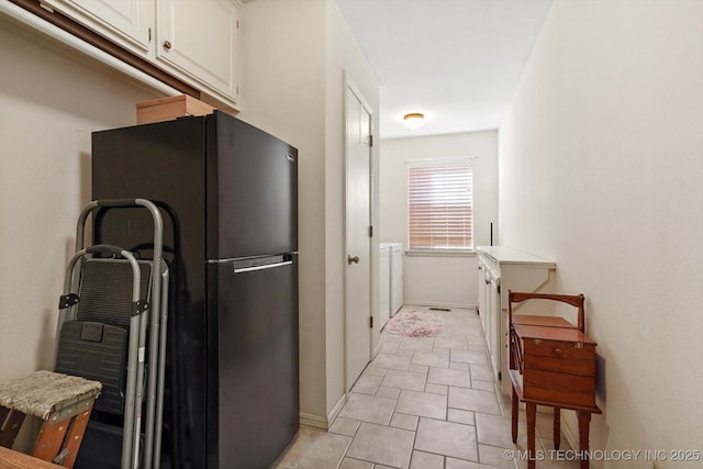 kitchen featuring baseboards, light countertops, freestanding refrigerator, and white cabinetry