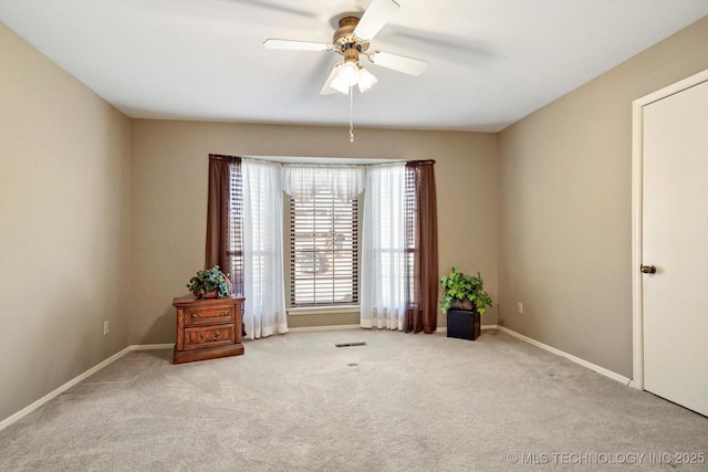 carpeted spare room featuring a ceiling fan, visible vents, and baseboards