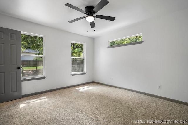 carpeted empty room featuring ceiling fan and baseboards