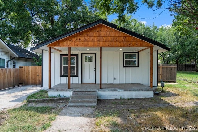 bungalow-style home with board and batten siding, covered porch, and fence