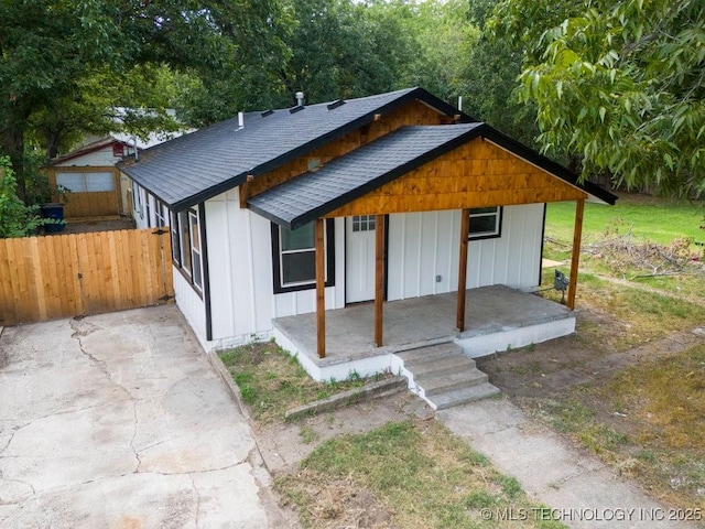 view of front of property featuring a shingled roof, fence, a porch, and board and batten siding