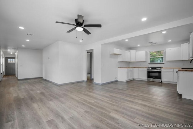 unfurnished living room featuring baseboards, visible vents, light wood-type flooring, a sink, and recessed lighting