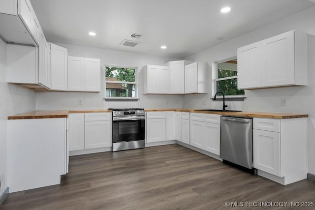 kitchen with dark wood-style floors, appliances with stainless steel finishes, butcher block countertops, and a sink