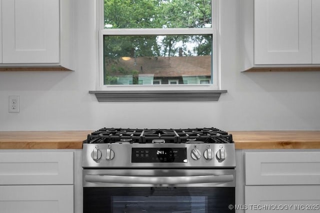 kitchen featuring wood counters, stainless steel range with gas stovetop, and white cabinetry