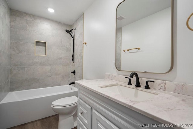 bathroom featuring visible vents, toilet, wood finished floors, vanity, and shower / bathing tub combination