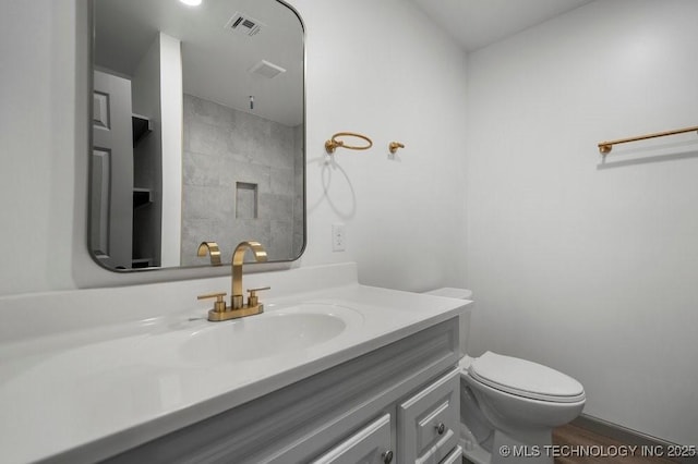 bathroom featuring toilet, wood finished floors, vanity, and visible vents