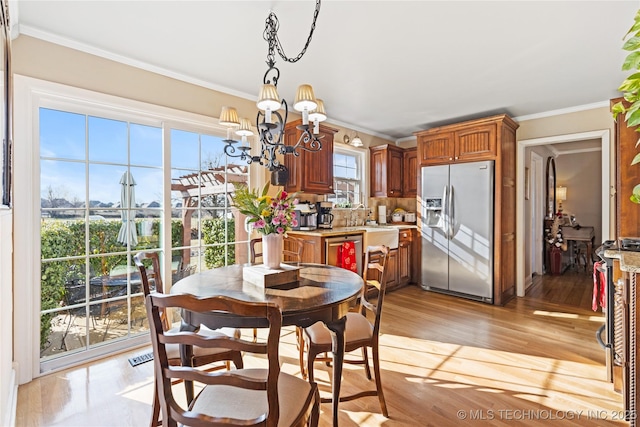 dining area featuring light wood-style flooring, a chandelier, and ornamental molding