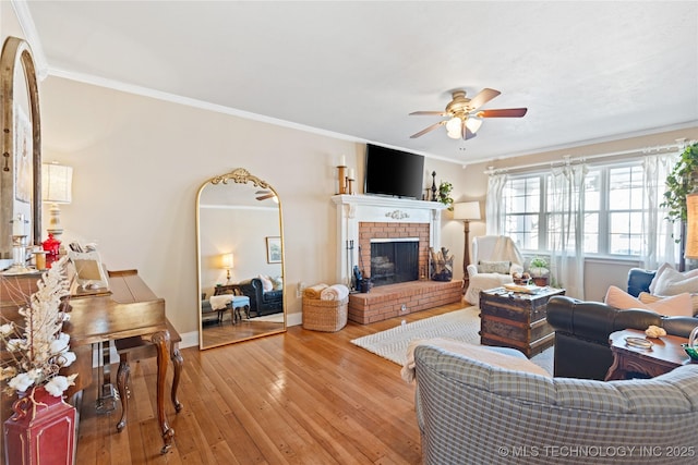 living room featuring crown molding, light wood finished floors, ceiling fan, and a brick fireplace