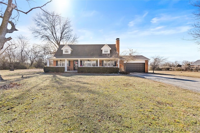 cape cod home featuring driveway, a chimney, covered porch, a front yard, and a garage