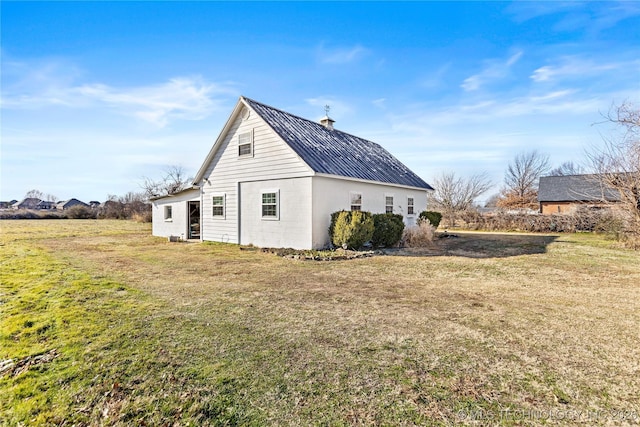 exterior space with metal roof and a yard