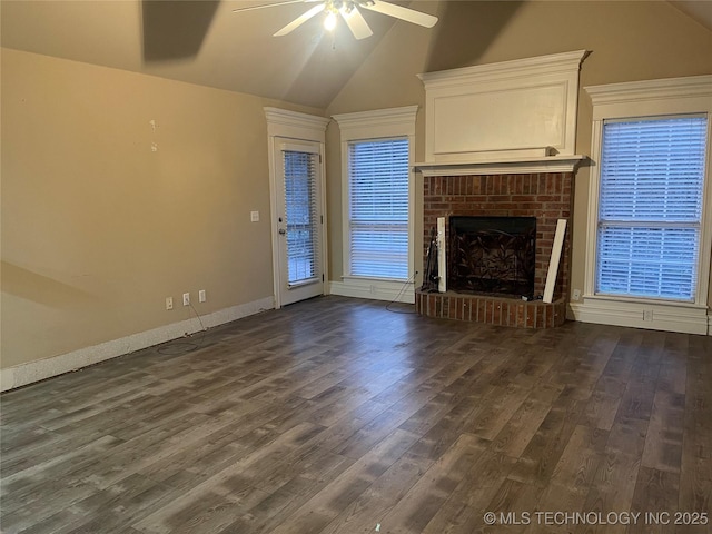 unfurnished living room with a ceiling fan, baseboards, dark wood-type flooring, vaulted ceiling, and a brick fireplace