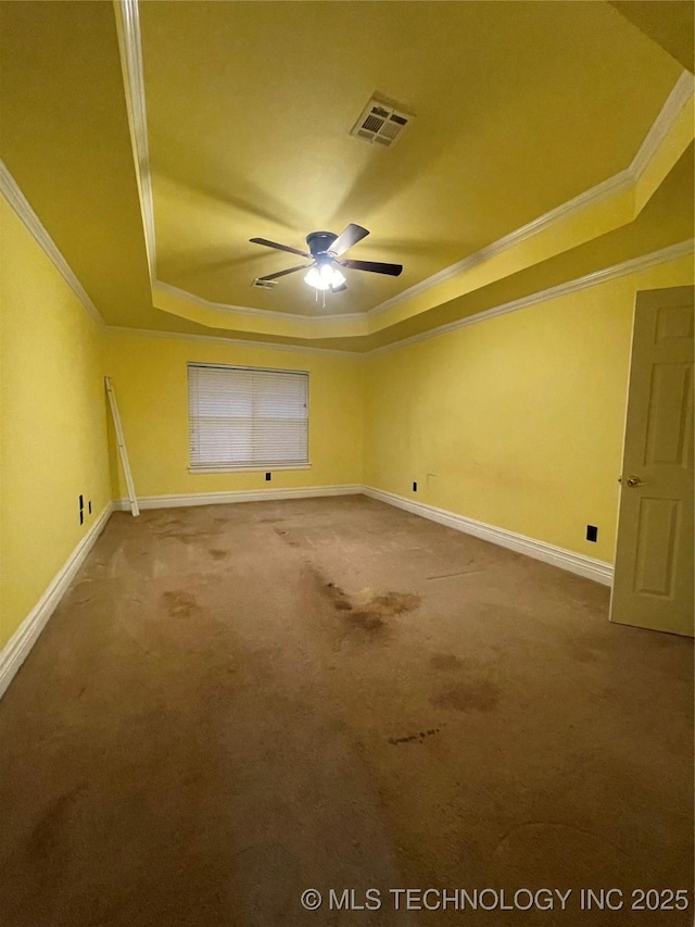 carpeted empty room with visible vents, a raised ceiling, baseboards, and a ceiling fan