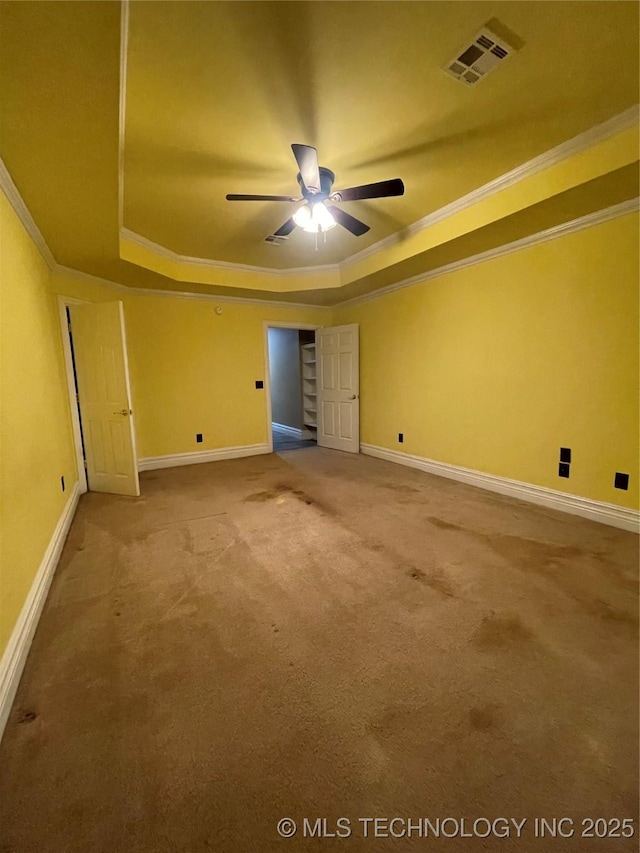 empty room featuring visible vents, crown molding, baseboards, carpet floors, and a raised ceiling