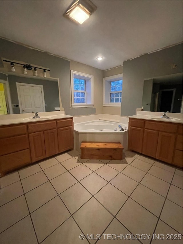 full bath featuring two vanities, tile patterned floors, a bath, and a sink