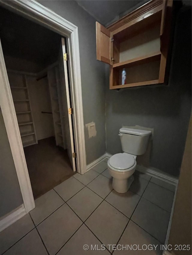 bathroom with baseboards, toilet, and tile patterned flooring