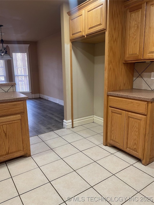 kitchen with decorative light fixtures, light tile patterned flooring, decorative backsplash, baseboards, and a chandelier