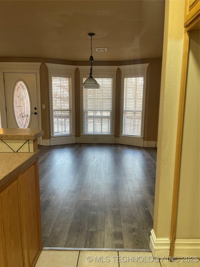 unfurnished dining area with visible vents, dark wood-style floors, and baseboards